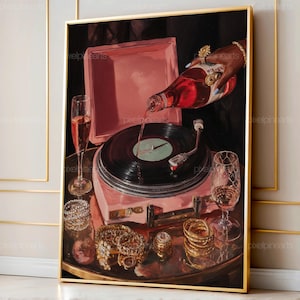 May include: A framed artwork depicts a pink record player with a black vinyl record. A bottle of red liquid is being poured onto the record. Champagne glasses, jewelry, and a pink tray are also visible, creating a luxurious theme.