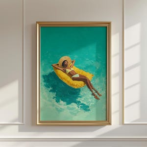 May include: A framed art print depicts a person relaxing on a yellow pool float in turquoise water. The person wears a yellow bikini and a wide-brimmed hat. The artwork is framed in a gold-colored frame and is mounted on a white wall.