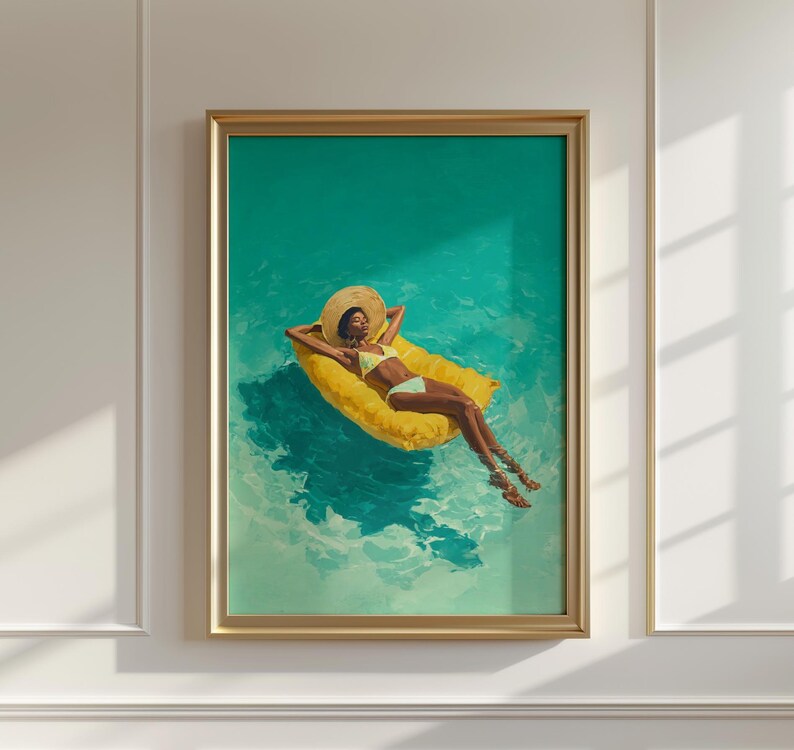 May include: A framed art print depicts a person relaxing on a yellow pool float in turquoise water. The person wears a yellow bikini and a wide-brimmed hat. The artwork is framed in a gold-colored frame and is mounted on a white wall.
