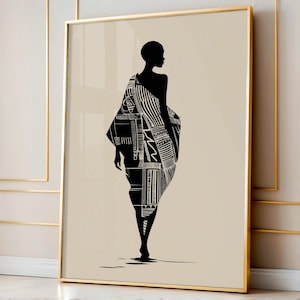 May include: Framed art print depicting a black and white silhouette of a person in a patterned garment. The artwork has a beige background and a gold frame. The garment features geometric and linear designs, creating a striking contrast.