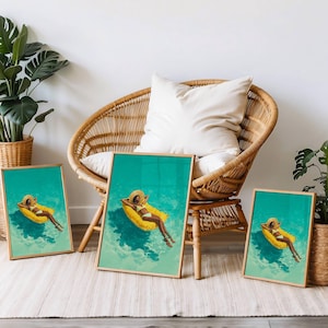 May include: Three framed art prints featuring a person relaxing on a yellow pool float in turquoise water. The person wears a straw hat and a white bikini. The prints have gold frames and are displayed near a wicker chair.