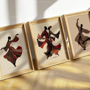 May include: Three framed wall art prints featuring silhouettes of figures in flowing garments. The left print shows a single figure in a red patterned robe, the center shows two figures dancing, and the right shows a single figure in a tan robe.