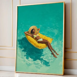 May include: A framed art print depicts a person relaxing on a yellow inflatable raft in turquoise water. The person wears a straw hat and a yellow bikini. The artwork is framed in a gold-colored frame.