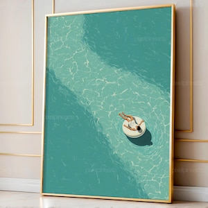 May include: A framed art print depicts a person relaxing on a white inflatable ring in a turquoise pool. The artwork has a minimalist style, with a gold frame and a focus on the water's texture and light reflections. The person is wearing a white outfit.