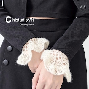 May include: A black long-sleeved cardigan and matching skirt set featuring cream-coloured, ruffled, crocheted lace cuffs. The text "ChistudioVN Crochet pattern" is visible on the left side of the black fabric. The cardigan has black buttons.