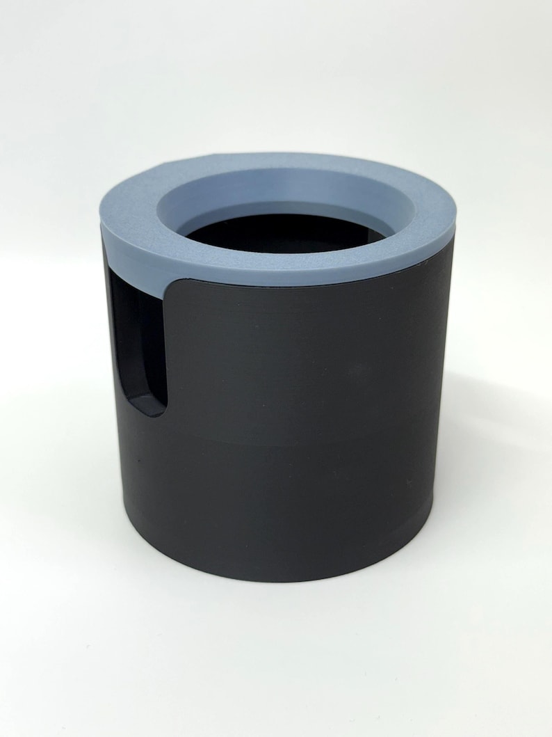 Puede incluir: Un recipiente cil&iacute;ndrico negro con un borde azul claro. El recipiente tiene un recorte en un lado. El interior es negro. Podr&iacute;a ser un organizador de escritorio o un art&iacute;culo similar.