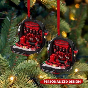 May include: Two black and red tool bag Christmas tree ornaments suspended by red ribbons. Each ornament is packed with red tools and features the text "Your Name". The words "PERSONALIZED DESIGN" are at the bottom.