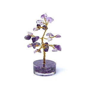 Könnte beinhalten: Ein dekorativer Amethyst-Edelsteinbaum mit einem goldfarbenen Drahtstamm und Ästen. Der Baum hat kleine, polierte Amethyststeine als Blätter und steht auf einem runden, transparenten Sockel, der mit Amethystchips gefüllt ist. Der Baum ist etwa 15 cm hoch.