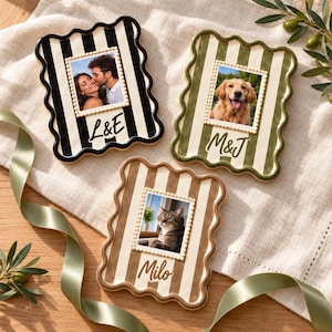 May include: Three rectangular photo frames with wavy edges and vertical stripes. One frame is black and white with L&E, one is olive green and white with M&J, and one is tan and white with Milo. Each frame features a central photo insert.