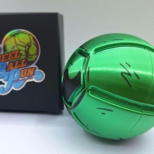 May include: A green metallic ball with black accents and etched lines, next to a black box with a logo that reads "Steel Ball Run". The ball has a soccer ball design.