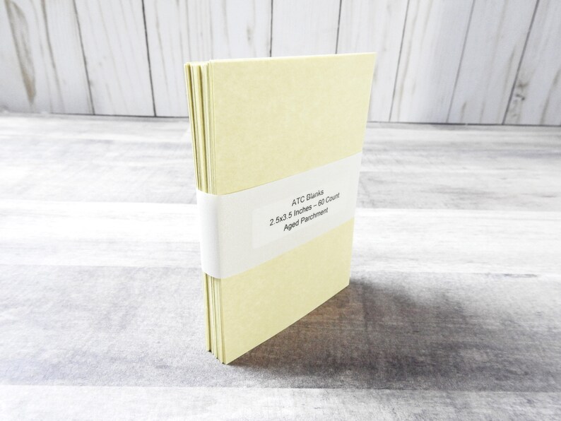 May include: A stack of 60 blank ATC cards in a pale yellow color, with a label that reads "ATC Blanks 2.5x3.5 Inches - 60 Count Aged Parchment".