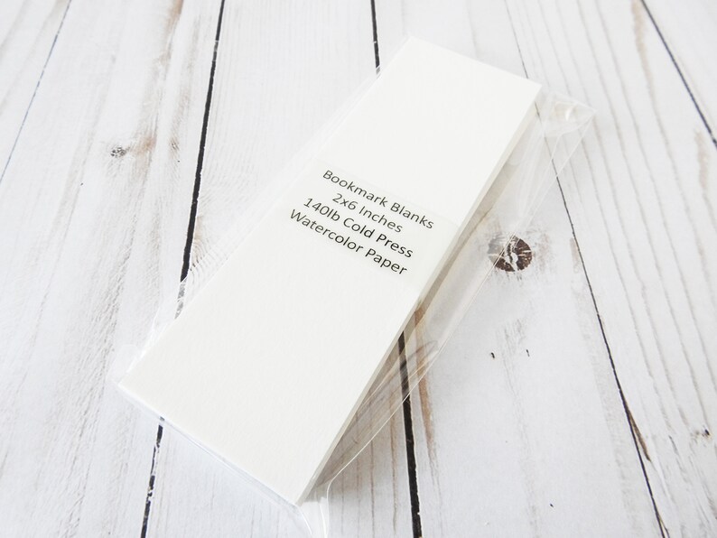 May include: A pack of white bookmark blanks made of 140lb cold press watercolor paper. The pack is 2x6 inches.