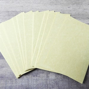 May include: A stack of 12 blank, off-white, textured paper sheets.