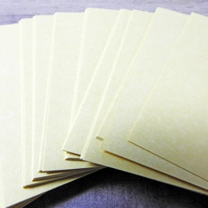 May include: A stack of blank, off-white index cards, fanned out in a semi-circle.