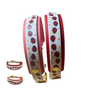 May include: Two wrap-around bracelets featuring a white band with a repeating pattern of red ladybugs and small yellow and orange flowers. The bracelets have a solid red interior lining, gold-toned metal snap closures, and a textured surface finish.