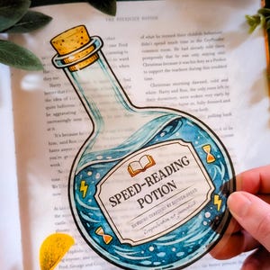Puede incluir: Una pegatina transparente con forma de botella de poción con tapón de corcho. La etiqueta dice "Speed-Reading Potion" con un diseño de líquido azul. Incluye rayos y relojes de arena.