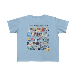 May include: Light blue children's t-shirt with a colorful alphabet design featuring illustrations of biblical figures and scenes. The shirt has the text "You are the light of the world!" and "Matthew 5:14" printed on it.