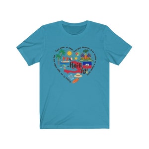 May include: A turquoise blue t-shirt with a circular design featuring the outline of Haiti, the Haitian flag, and various icons representing the country. The text "Tout moun se menm" and "Everyone deserves to be treated as a human being" are written around the design.