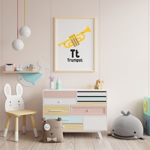 Op de afbeelding: Een witte houten stoel in de vorm van een konijn met een lichtroze borst en een lichtblauwe walviswanddecoratie. Een witte commode met roze, blauwe en houten laden. Een ingelijste print met een gele trompet en de tekst "Tt Trompet".