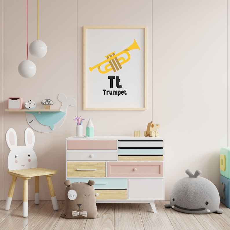 Op de afbeelding: Een witte houten stoel in de vorm van een konijn met een lichtroze borst en een lichtblauwe walviswanddecoratie. Een witte commode met roze, blauwe en houten laden. Een ingelijste print met een gele trompet en de tekst "Tt Trompet".