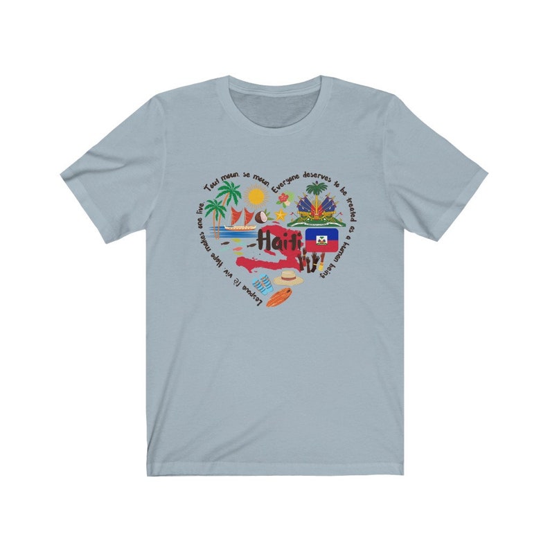 May include: Light blue t-shirt with a graphic design of the island of Haiti. The design includes the Haitian flag, palm trees, a boat, a coconut, and the text "Tout moun se moun, Lespwe f&egrave; viv. Hope makes us live, Everyone deserves to be treated as a human being."