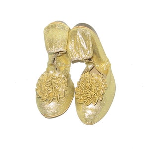 Op de afbeelding: Een paar gouden glitter ballerina's met een gerimpeld detail op de teen.