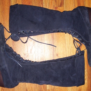 May include: A pair of dark blue suede knee-high boots with lace-up fronts and block heels.