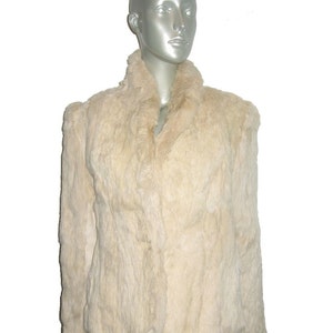 Puede incluir: Una chaqueta de piel blanca con cuello. La chaqueta está hecha de piel suave y esponjosa y tiene un diseño clásico y atemporal.