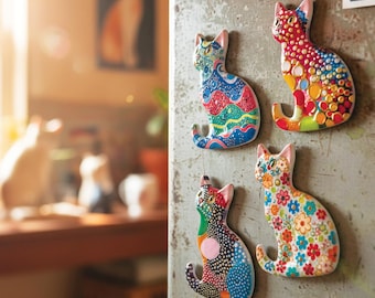 Puede incluir: Cuatro imanes decorativos con forma de gato con varios diseños. Uno presenta un diseño azul, rojo y verde, otro tiene un patrón de puntos rojos, amarillos y naranjas, un tercero tiene un estampado floral y el último un diseño de patchwork.