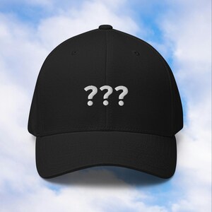 Könnte beinhalten: Schwarze Baseballkappe mit gebogenem Schirm. Die Kappe hat drei weiße, gestickte Fragezeichen auf der Vorderseite. Der Hut ist aus weichem Material und hat eine strukturierte Passform.