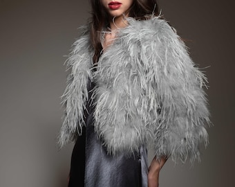 May include: A woman wearing a gray feather boa over a gray satin dress.