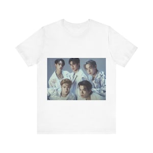 May include: White t-shirt featuring a group photo of five people. The image on the shirt shows the group in white and silver outfits. The t-shirt is made of a soft, comfortable material.