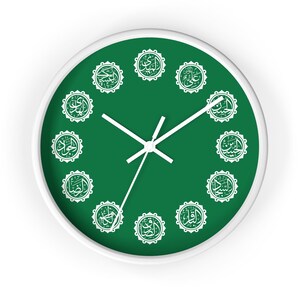 Pode incluir: Relógio de parede com moldura branca e mostrador verde. O mostrador do relógio apresenta caligrafia árabe branca em um padrão circular. Os ponteiros brancos indicam as horas. O design do relógio é simples e elegante.