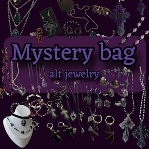 Op de afbeelding: Een verzameling alternatieve sieraden, waaronder kettingen, oorbellen, ringen en armbanden, tegen een donkerpaarse achtergrond. De afbeelding toont de tekst "Mystery bag" en "alt jewelry". De sieraden hebben gotische en edgy ontwerpen.