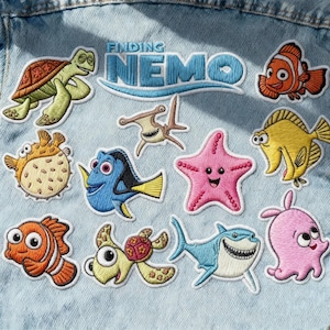 May include: Embroidered patches featuring characters from the movie "Finding Nemo." The patches include Nemo, Dory, Crush, and other sea creatures in vibrant colors. The patches are on a light blue denim background.