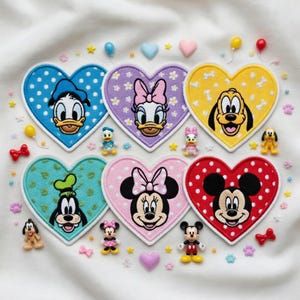 Può includere: Sei toppe ricamate a forma di cuore con personaggi Disney: Paperino su pois blu, Paperina su fiori viola, Pluto su ossa gialle, Pippo su trifogli turchesi, Minni su pois rosa e Topolino su pois rossi.