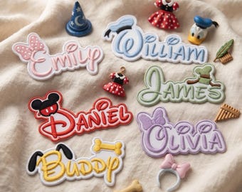 May include: A collection of embroidered name patches featuring Disney-themed designs. The patches display the names Emily, William, James, Daniel, Olivia, and Buddy, accompanied by small decorative items like a wizard hat, dresses, and bones.