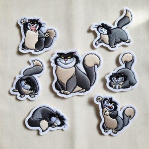 May include: A collection of seven embroidered patches featuring a cartoon cat in various poses. The cat has black fur, a tan chest, and a fluffy tail. Each patch has a white border, and the cat's expressions range from playful to grumpy.