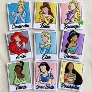 Peut inclure: Neuf écussons brodés représentant des princesses Disney : Cendrillon, Belle, Raiponce, Ariel, Elsa, Jasmine, Tiana, Blanche-Neige et Pocahontas. Chaque écusson a une bordure blanche et le nom de la princesse en dessous.
