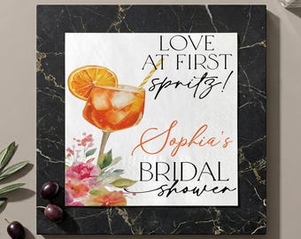 Gepersonaliseerde cocktailservetten met de tekst "Love at First Spritz", servetten voor een vrijgezellenfeest met sinaasappelsmaak.