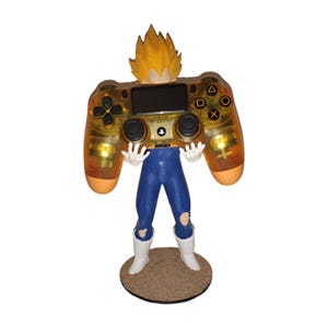 Könnte beinhalten: Figur einer Figur aus Dragon Ball Z, die einen goldfarbenen Videospiel-Controller hält. Die Figur hat stachelige gelbe Haare, eine blaue Hose, weiße Stiefel und weiße Handschuhe. Der Controller hat schwarze Knöpfe und einen schwarzen Bildschirm.