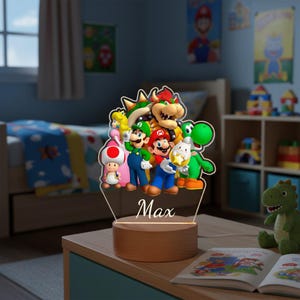 May include: A decorative night light featuring a group of cartoon characters, including Mario, Luigi, and Yoshi. The characters are in vibrant colors and are set against a clear acrylic panel. The base is made of wood, and the name "Max" is written on the panel.