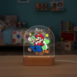 May include: A wooden-based night light featuring a colorful illustration of Mario, Luigi, and Yoshi. The characters are depicted in their signature outfits. The name "Max" is printed above the characters. The light is on a wooden base.