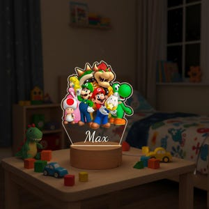 May include: A night light featuring a group of colorful characters from the Super Mario video game series. The light has a wooden base and a clear acrylic top with the name "Max" engraved on it. The characters include Mario, Luigi, Yoshi, and Bowser.