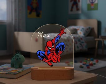 May include: A Spiderman-themed night light with a wooden base. The clear acrylic panel features a red and blue Spiderman graphic and the name "Max" in white. The lamp is on a wooden table in a child's bedroom.