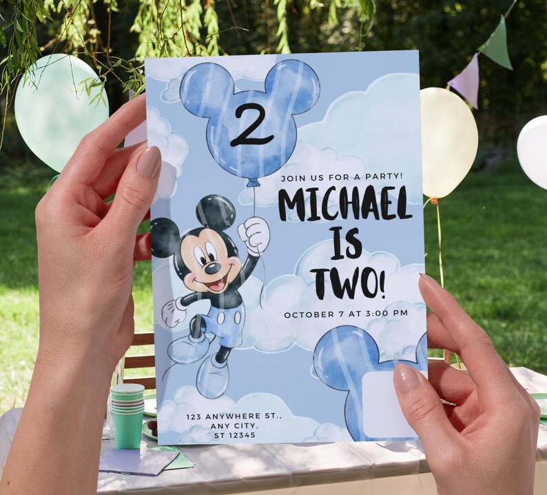 May include: A rectangular birthday party invitation card featuring a light blue sky background with white clouds. The card displays a cartoon mouse character holding a blue balloon shaped like a mouse head with the number 2. Text reads: JOIN US FOR A PARTY! MICHAEL IS TWO! OCTOBER 7 AT 3:00 PM 123 ANYWHERE ST., ANY CITY, ST 12345.