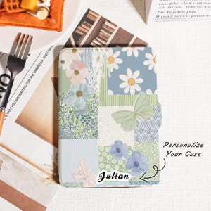 May include: A floral patterned phone case with a patchwork design. The case features daisies, butterflies, and blue and green floral patterns. The name "Julian" is printed on the case, with the text "Personalize Your Case" nearby.