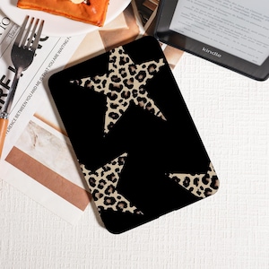 Puede incluir: Funda negra para tableta con dos grandes estrellas con estampado de leopardo. La funda es rectangular y parece estar hecha de un material duradero. El diseño es un contraste audaz de negro y beige.