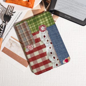 May include: A patchwork Kindle cover featuring a mix of patterns: red gingham, green plaid, and denim. Decorative elements include lace trim and apple-shaped buttons. The cover is designed to protect the e-reader.