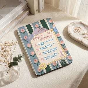 Può includere: Un blocco note decorativo con un design floreale e a righe. Il blocco note presenta il testo "things to remember" e promemoria scritti a mano con inchiostro blu. Fiori rosa ed elementi decorativi circondano il testo.